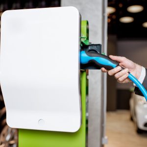 Man plugging cable into the charging station for electric cars at the car dealership, close-up view