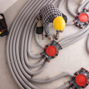 Modern Residential Heat Recuperation System Pipelines Installed by Professional Caucasian HVAC Technician in His 40s. Heat Ventilation Recovery Technology.